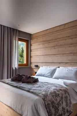 a bedroom with a large bed with a wooden wall at Suite Mia in Falcade