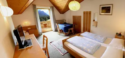 a living room with two beds and a table and a room at Gasthof zum Schlern in Fiè