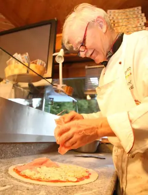 a man is making a pizza on a counter at Gasthof zum Schlern in Fiè