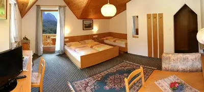 a bedroom with two beds and a living room at Gasthof zum Schlern in Fiè