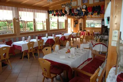 a restaurant with white tables and chairs and windows at Gasthof zum Schlern in Fiè
