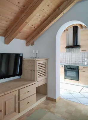 a kitchen with wooden cabinets and a flat screen tv at Maurerhof Apartments Kronplatz in San Lorenzo di Sebato