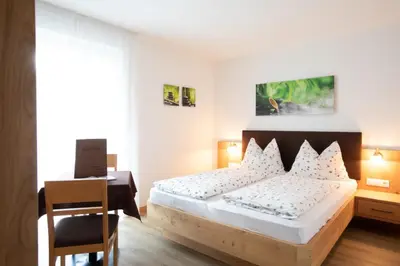 a bedroom with a bed and a desk and a table at Garni Pircher in Tirolo