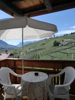 a table with two chairs and an umbrella on a porch at Garni Pircher in Tirolo