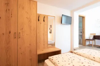 a bedroom with a wooden cabinet and a bed at Garni Pircher in Tirolo