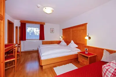 a bedroom with a large bed and a red couch at Hotel Garni Aghel in Selva di Val Gardena