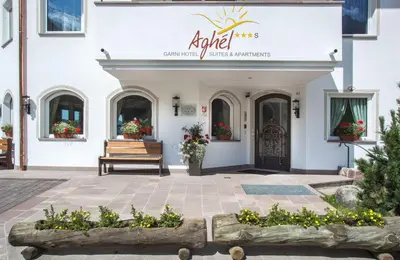 a building with a bench and flowers in front of it at Apartments Aghel ***S in Selva di Val Gardena