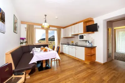 a living room and kitchen with a table and a couch at Apartments Aghel ***S in Selva di Val Gardena