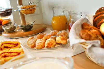 a table topped with plates of pastries and orange juice at Apartments Aghel ***S in Selva di Val Gardena