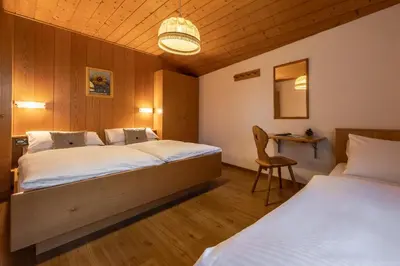 a bedroom with two beds and a table and a chair at Villa Resi Apartments in Corvara in Badia