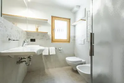 a white bathroom with a sink and a toilet at Villa Resi Apartments in Corvara in Badia