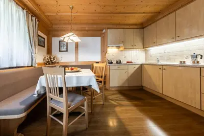 a kitchen with a table and chairs in a room at Villa Resi Apartments in Corvara in Badia