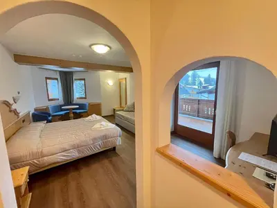 a hotel room with a bed and a room with a window at Hotel Villa Aurora in San Martino di Castrozza