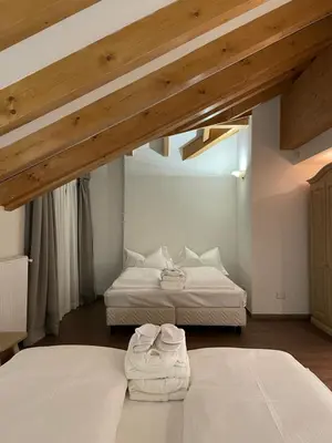 two beds in a room with wooden ceilings at Hotel Villa Aurora in San Martino di Castrozza