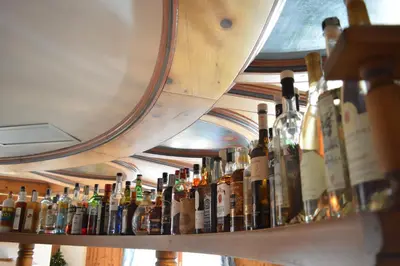 a shelf filled with lots of bottles of alcohol at Hotel Villa Aurora in San Martino di Castrozza