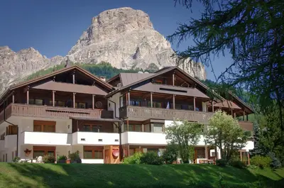 a large building with a mountain in the background at Appartamenti Pastüres in Colfosco