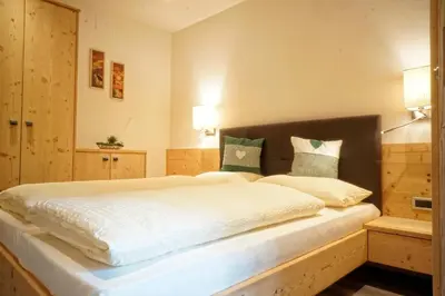 a bedroom with a large bed with white sheets at Appartamenti Pastüres in Colfosco