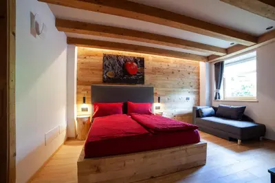 a bedroom with a red bed and a chair at B&B fiordimelo in Cavalese