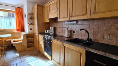 a kitchen with wooden cabinets and a black dishwasher at Appartamento Cesa Lamar in Canazei