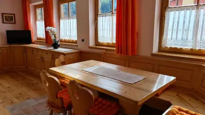a dining room with a wooden table and windows at Appartamento Cesa Lamar in Canazei