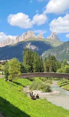 two people are sitting in a river under a bridge at Appartamento Cesa Lamar in Canazei