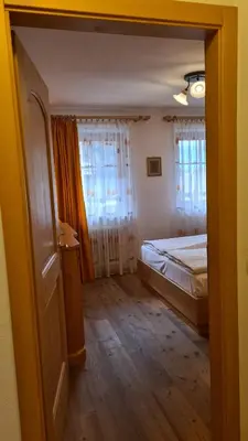 a bedroom with a bed and two windows at Appartamento Cesa Lamar in Canazei