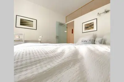 a white bedroom with a large white bed at In Urbi, city appartement in Bressanone