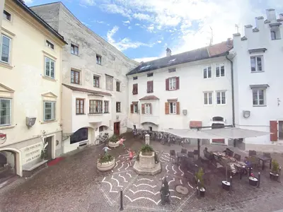 an open courtyard with tables and chairs and buildings at In Urbi, city appartement in Bressanone