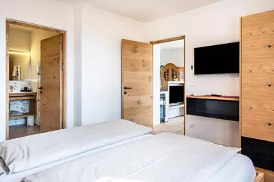 a bedroom with a white bed and a television at Nofnerhof in Appiano sulla Strada del Vino