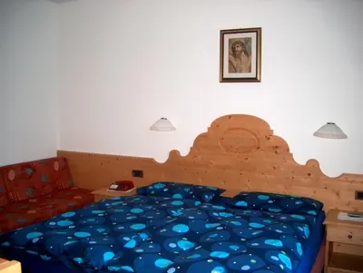 a bedroom with a bed and a red couch at Hotel Rosalpina in Rocca Pietore