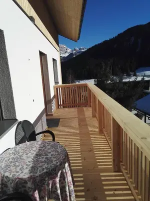 a wooden deck with a table and chairs on it at Apartments Gana in La Villa