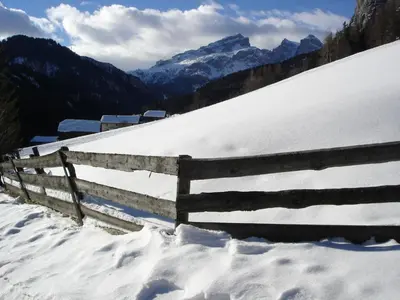 a fence on a snow covered hill with mountains at Apartments Gana in La Villa