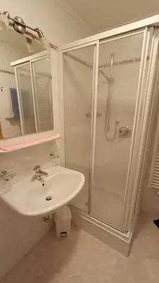 a white bathroom with a shower and a sink at Apartments Gana in La Villa