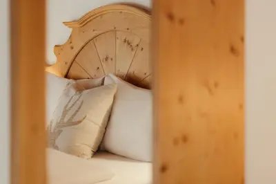 a bed with a wooden headboard and pillows on it at Residence Ciasa Vedla in Badia