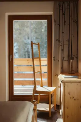 a wooden chair sitting in front of a window at Residence Ciasa Vedla in Badia