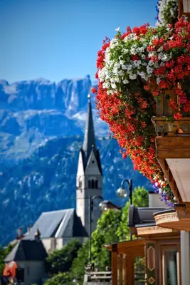 a bunch of flowers hanging from a building with a church at Hotel Cesa Padon in Arabba