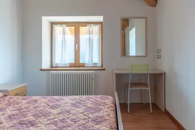 a bedroom with a bed and a desk and a chair at Appartamento alla Brisa Grauno Ospitar in Grauno