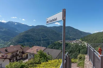 a street sign on a hill with mountains in the background at Appartamento alla Brisa Grauno Ospitar in Grauno
