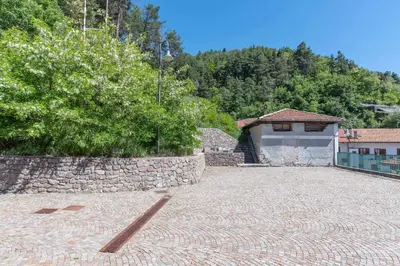 a stone parking lot with a stone wall and a building at Appartamento alla Brisa Grauno Ospitar in Grauno
