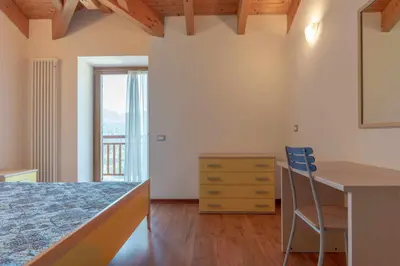 a bedroom with a bed and a desk and a window at Appartamento al Sol Grauno Ospitar in Grauno