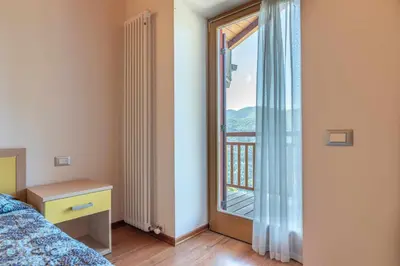 a bedroom with a bed and a window with a balcony at Appartamento al Sol Grauno Ospitar in Grauno