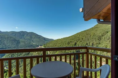 a table and chair on a balcony with mountains at Appartamento al Sol Grauno Ospitar in Grauno