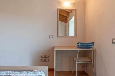 a bedroom with a desk and a mirror and a chair at Appartamento al Rio Grauno Ospitar in Grauno