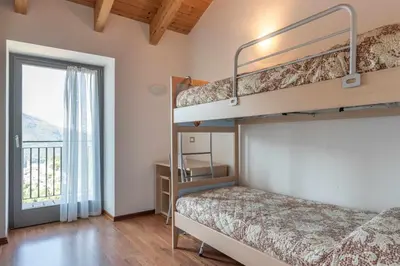 a bedroom with two bunk beds and a balcony at Appartamento al Rio Grauno Ospitar in Grauno