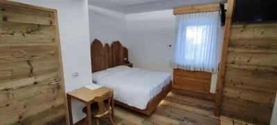 a bedroom with a bed and a table and a window at Hotel Venezia in Rocca Pietore