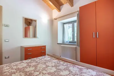a bedroom with a bed and a dresser and a window at Appartamento alla Preda Grauno Ospitar in Grauno