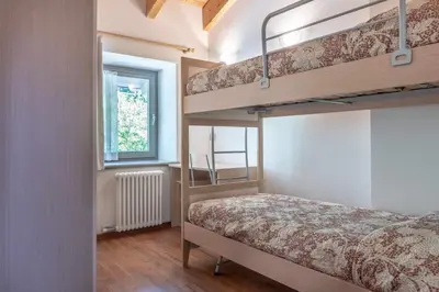 a bedroom with two bunk beds and a window at Appartamento alla Preda Grauno Ospitar in Grauno