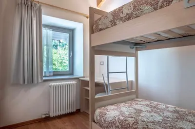 a bedroom with two bunk beds and a window at Appartamento alla Preda Grauno Ospitar in Grauno