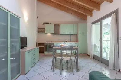 a kitchen with a table with chairs and a tv at Appartamento al Bosc Grauno Ospitar in Grauno