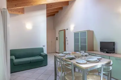 a dining room with a table and a green couch at Appartamento al Bosc Grauno Ospitar in Grauno